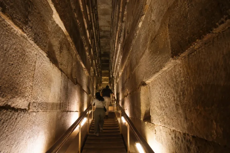 Visitor climbing the lit ascending passage inside the Great Pyramid