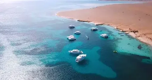 Boat tour to Orange Bay Hurghada - aerial view showing sparkling turquoise water, curved coastline, and boats approaching the island