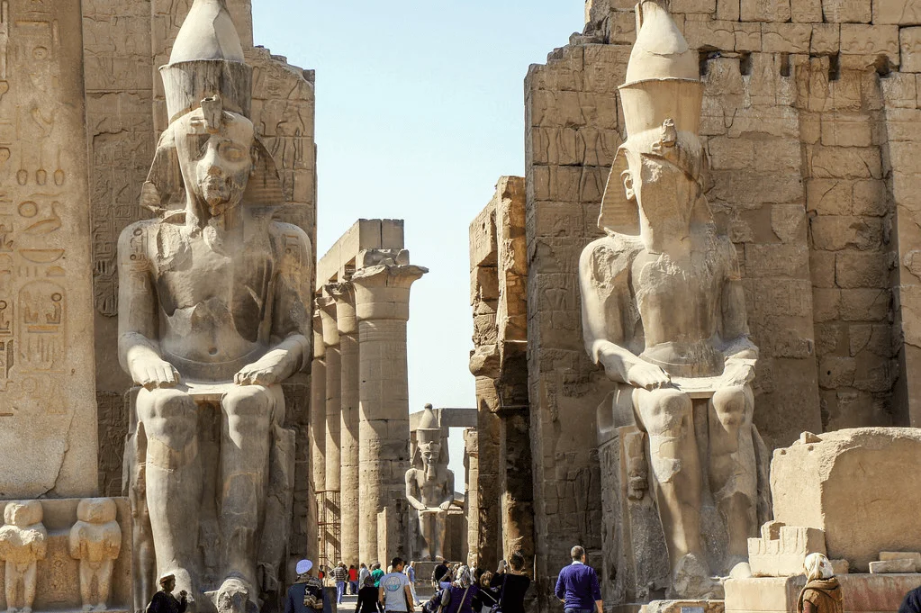 At the entrance to Luxor Temple colossal statues of Pharaoh Ramses II—carved from black granite and standing over 15 meters tall—rise to greet every visitor with timeless authority.